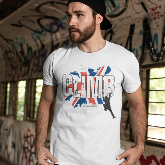 Man wearing white UK climbing community t-shirt with Union Jack and climber design in graffiti-covered room.